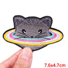 A gray cat face embroidered patch with a colorful rainbow border being held by a hand.