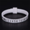 A white ring sizer measuring tool with numbered sizes is shown on a dark surface.