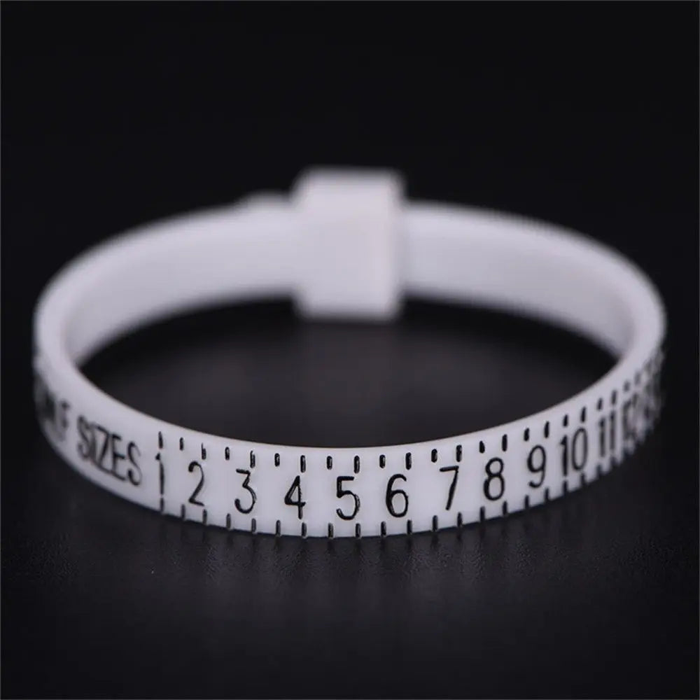 A white ring sizer measuring tool with numbered sizes is shown on a dark surface.
