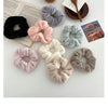 A collection of plush coil hair ties in various shades of pink, gray, and black arranged on a white surface.