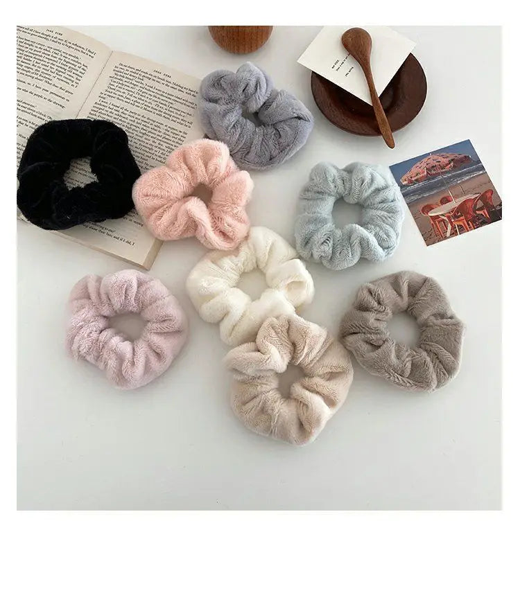 A collection of plush coil hair ties in various shades of pink, gray, and black arranged on a white surface.