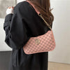 A woman holds a pink and black vintage-inspired PU leather crossbody bag with a gold chain accent.