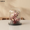 A clear glass cloche displays a small arrangement of pink and white artificial roses and greenery.