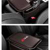 A dark brown car armrest box mat with an AS logo and a storage pocket is shown in a car interior.