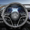 Close-up view of a black steering wheel with carbon fiber texture covers and digital instrument cluster.