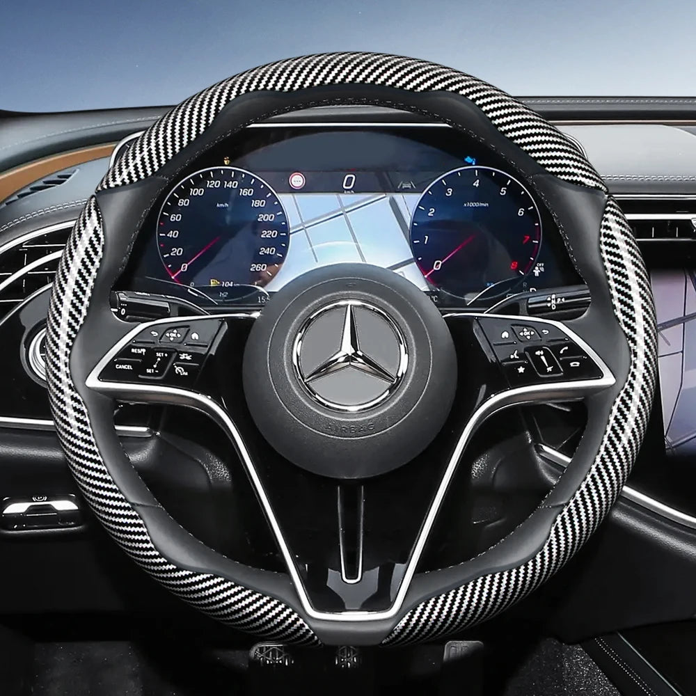 Close-up view of a black steering wheel with carbon fiber texture covers and digital instrument cluster.