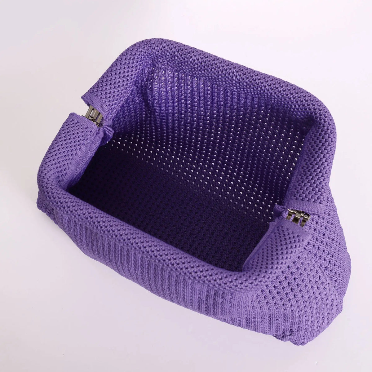 A purple hand-knit clutch bag with a textured surface and pearl accents.