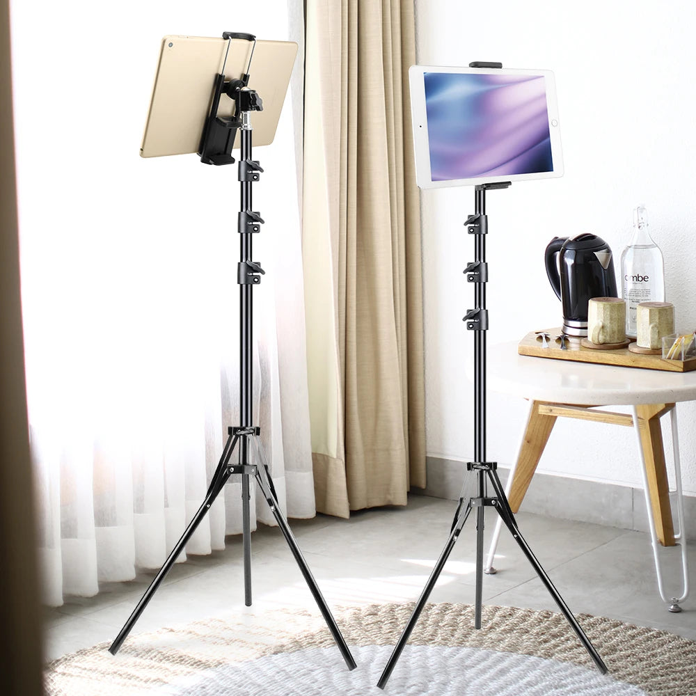 A black adjustable aluminum tripod stand is shown next to a tablet, set up in a bright indoor environment.