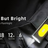 Eine kleine, gelb-leuchtende, portable Taschenlampe wird in einem dunklen Stoff gehalten und zeigt ihre Merkmale.