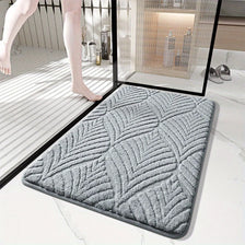 A gray plush velvet bathroom mat with a non-slip backing is shown on a white marble floor.