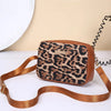 A brown leopard print crossbody bag with a tan leather strap is displayed on a white surface.