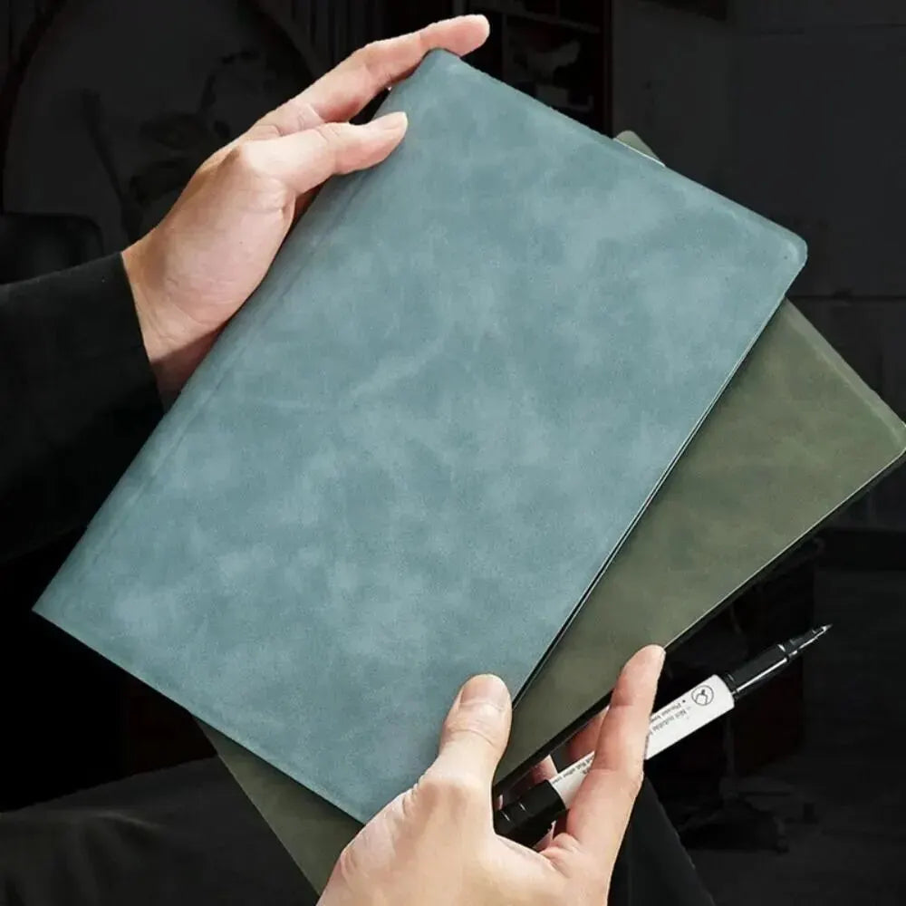 Une main tient un bloc-notes en cuir gris et un tableau assorti vert, montrant l'ensemble.