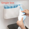A white single box dispenser for scented drawstring trash bags with handles is mounted on a wall.