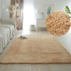 A fluffy beige accent rug placed on a light wood floor in a bright, minimalist room.