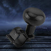 A black universal steering wheel spinner knob used as a one-hand driving aid, shown against a dark, moody background.