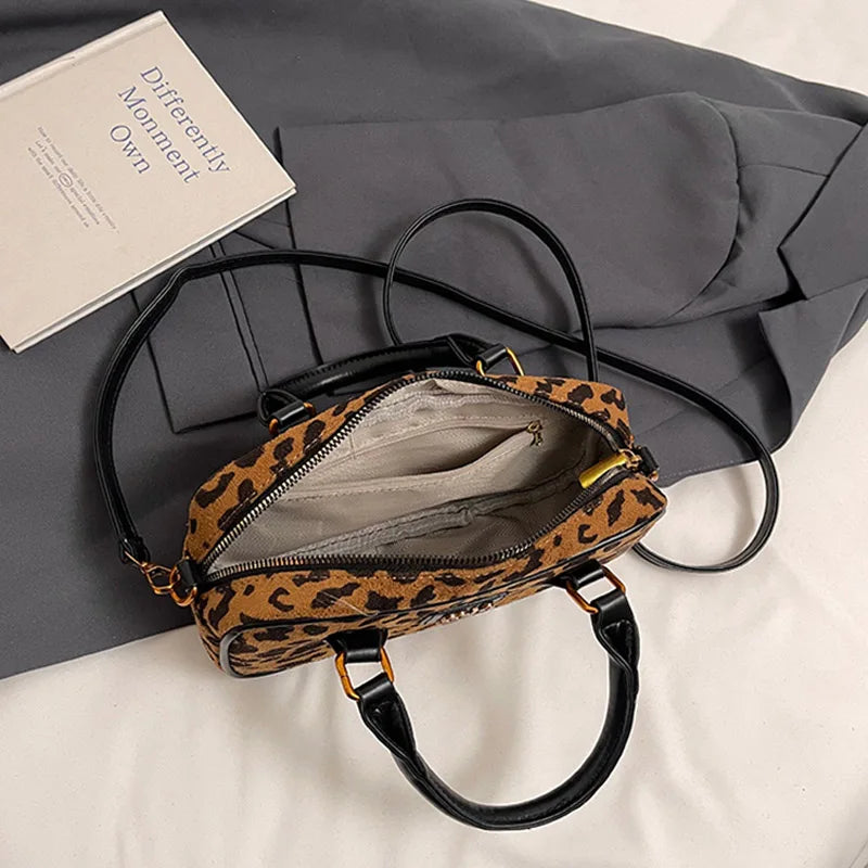 A brown and black leopard print retro hobo satchel bag with a gold hardware detail resting on a gray fabric.