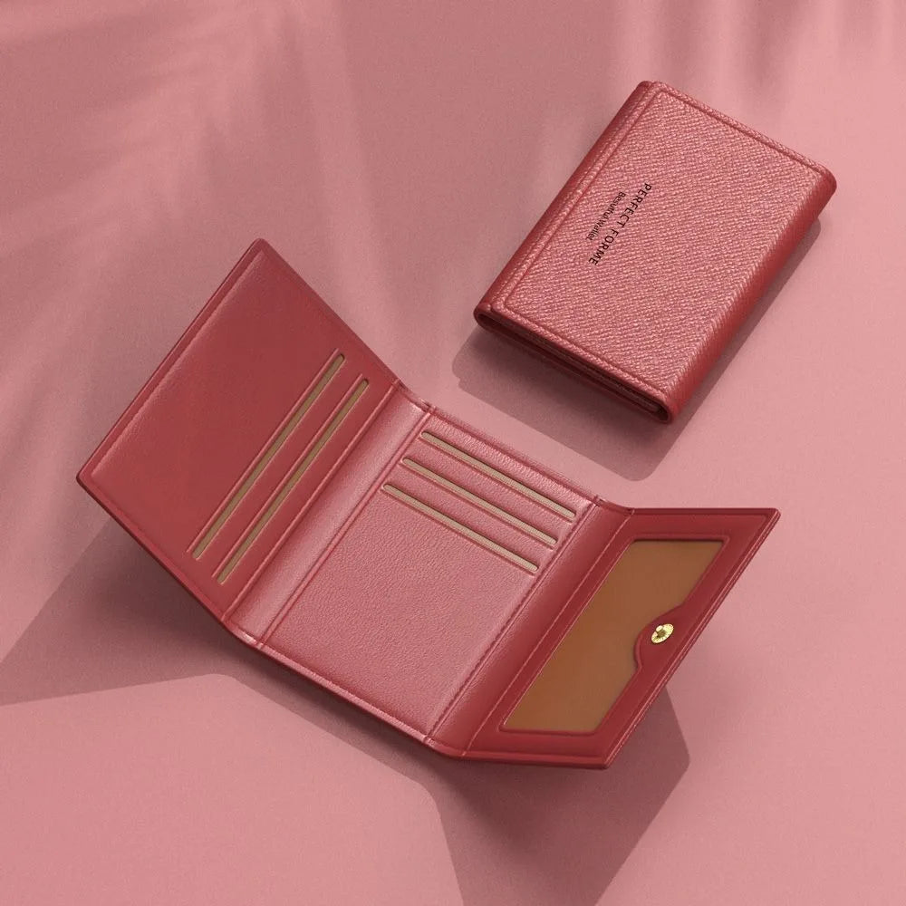 A pink leather card holder wallet with multiple slots shown open on a soft pink background.