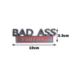 A black 3D metal badge emblem with the text BAD ASS EDITION and dimensions shown.