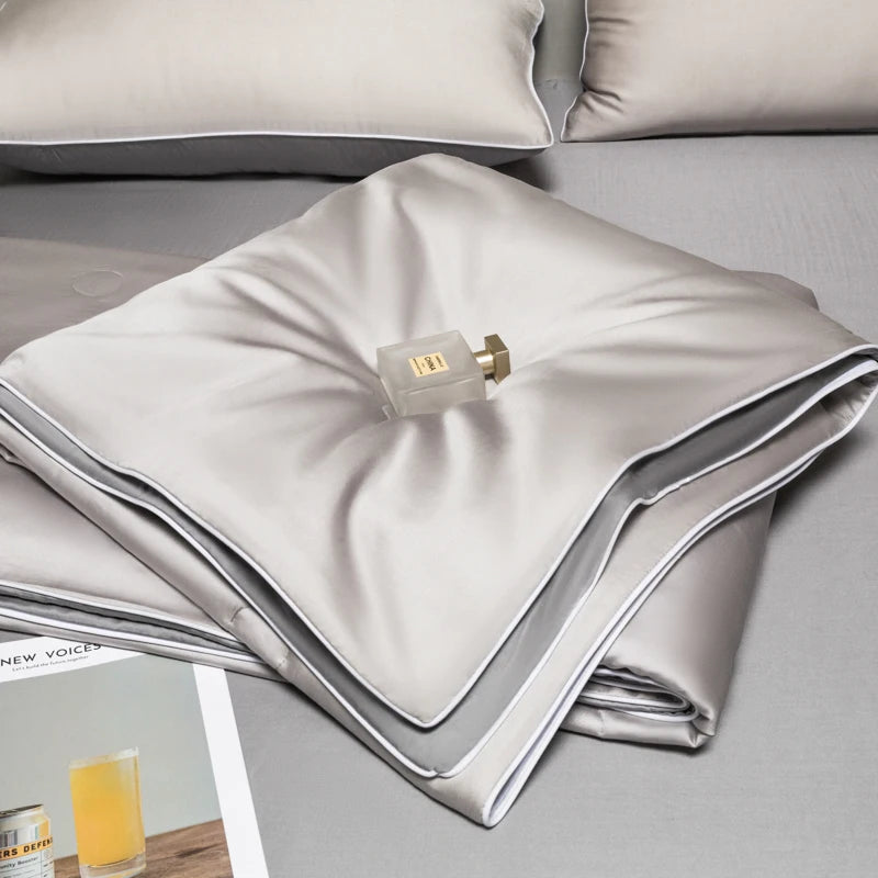 A folded light gray ice silk quilt with a brass zipper visible on the top layer.