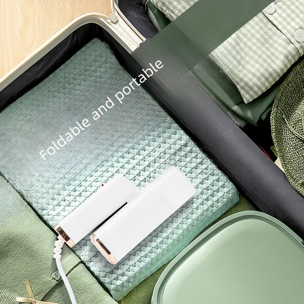 A white portable handheld garment steamer is shown inside a green foldable storage case.