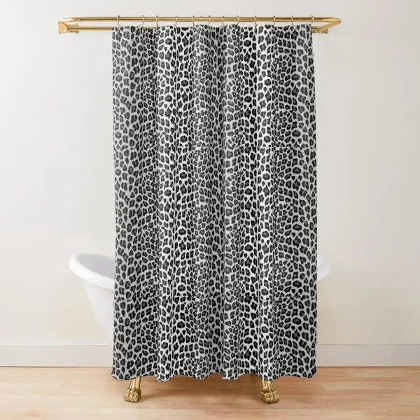 A black and white leopard print shower curtain hanging from a gold rod.