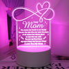 A glowing white heart-shaped sign with the text Dear Mom and a loving message, displayed on a round light base.
