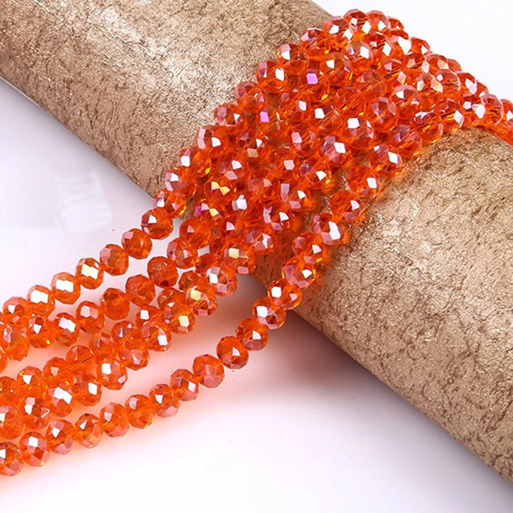 A strand of faceted orange crystal glass spacer beads is shown wrapped around a cylindrical object.