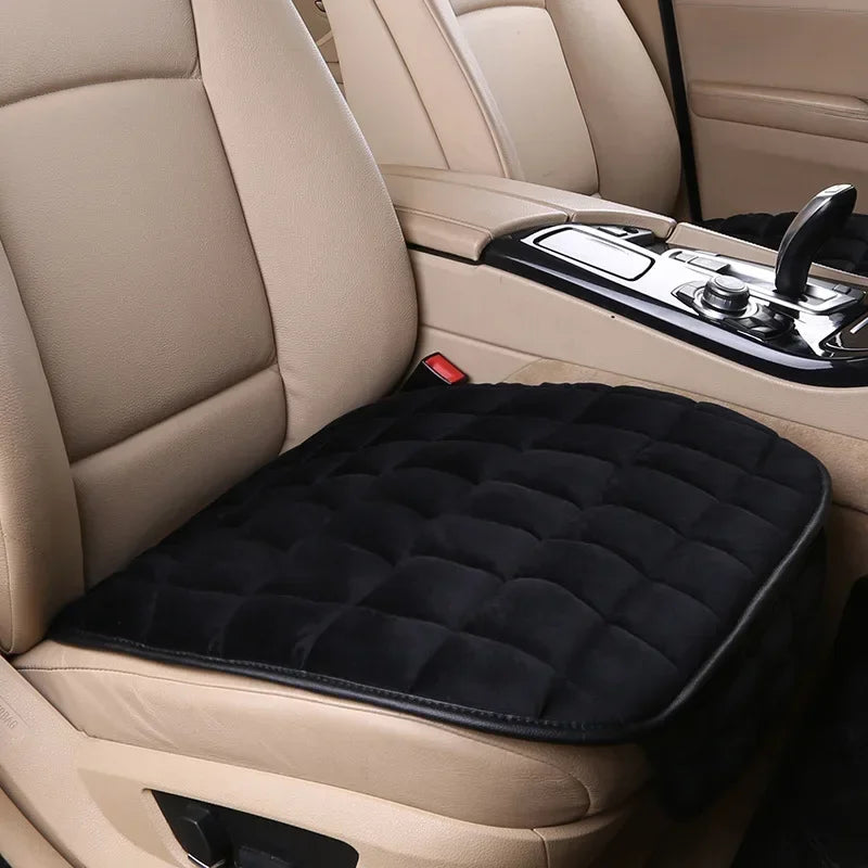 A close-up view of a beige car seat cover with black quilted padding on the front seat.