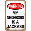 A vintage metal tin sign with a warning label that reads WARNING MY NEIGHBORS IS A JACKASS