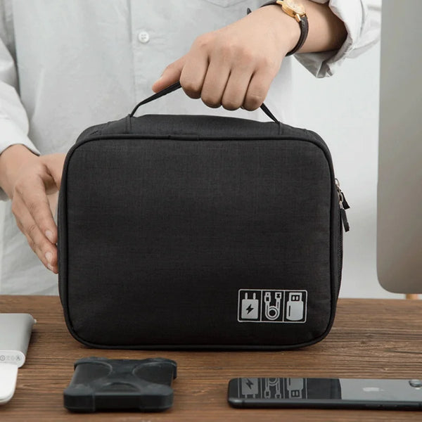Una bolsa portátil impermeable de almacenamiento de cables negra sostenida por una persona en una mesa de madera.