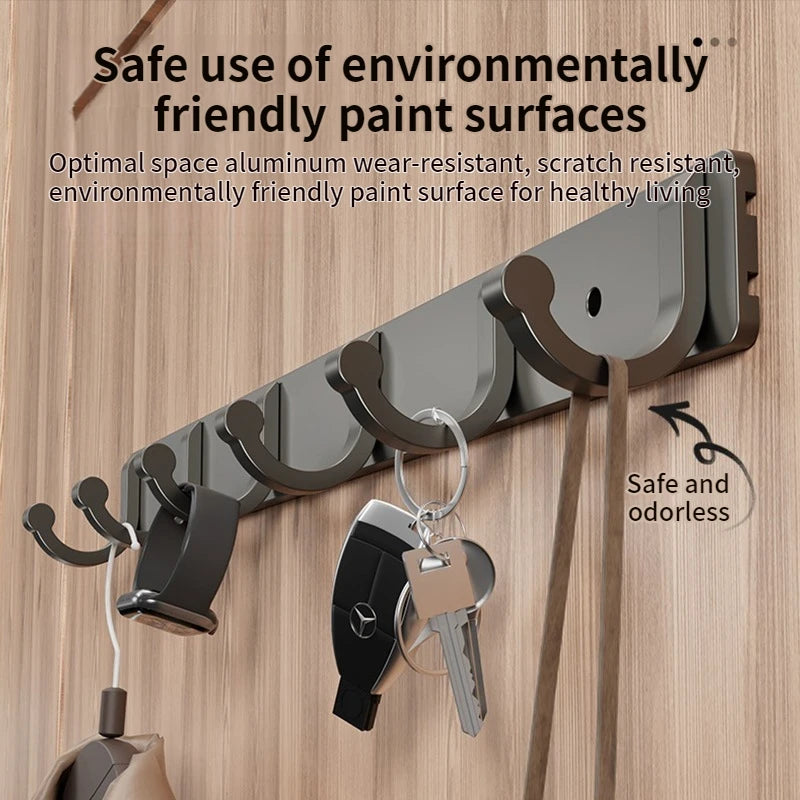 A set of six dark gray no-drill aluminum wall hooks with adhesive backing are shown mounted on a wooden surface.
