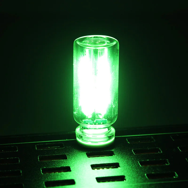 A glowing green glass accent LED night light resting on a dark green textured surface.