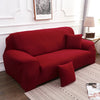 A deep red silky soft stretchable sofa cover displayed on a living room sofa.