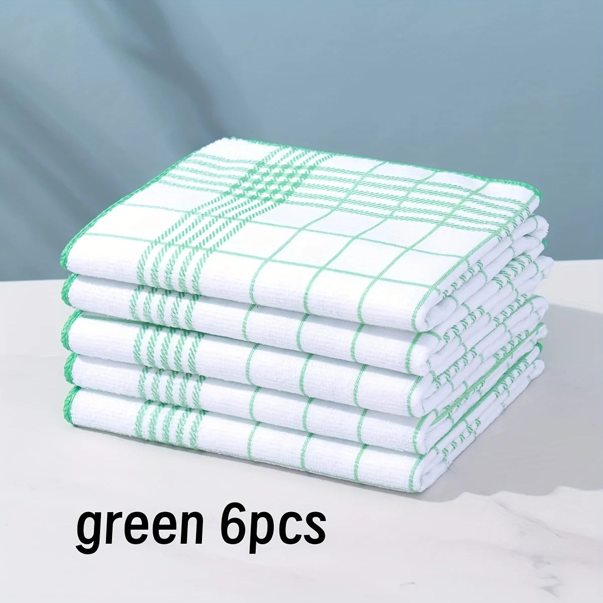 A stack of six green and white checkered lint-free dish cloths on a white surface.