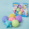 A box of soft textured sensory balls for babies in various colors and shapes, including purple, pink, yellow, and blue.