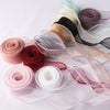 A collection of rolled and unwound wavy edge organza ribbon in various shades of pink, purple, beige, and black.