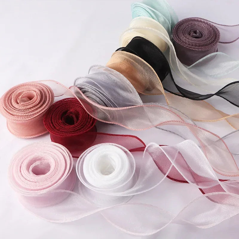 A collection of rolled and unwound wavy edge organza ribbon in various shades of pink, purple, beige, and black.