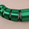 A roll of emerald green lustrous satin ribbon, shown in a row on a light background.
