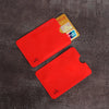 A set of red RFID blocking card sleeves is displayed on a dark surface next to a yellow card.