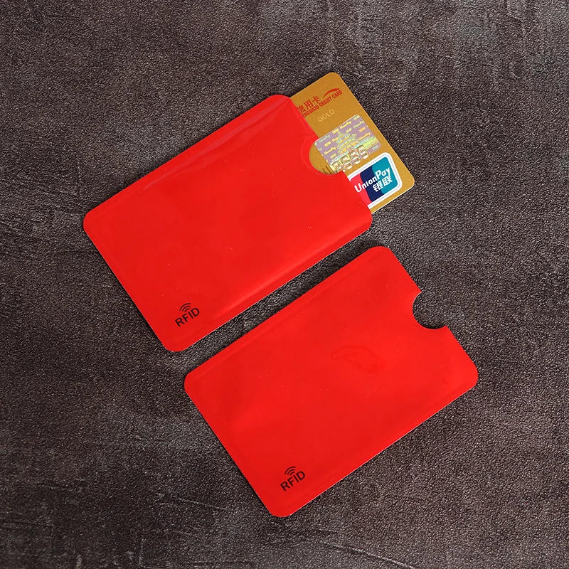A set of red RFID blocking card sleeves is displayed on a dark surface next to a yellow card.