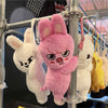 A pink rabbit plush doll is displayed on a metal rack alongside other white and yellow animal plush toys.