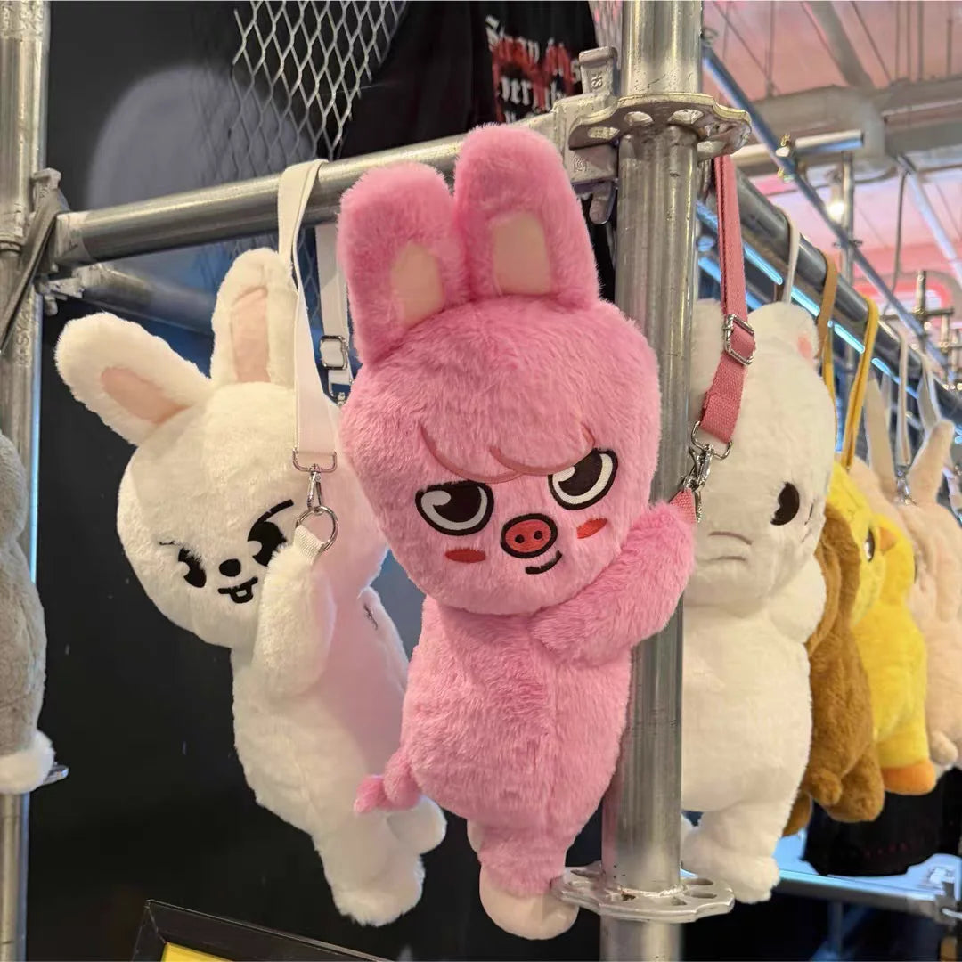 A pink rabbit plush doll is displayed on a metal rack alongside other white and yellow animal plush toys.