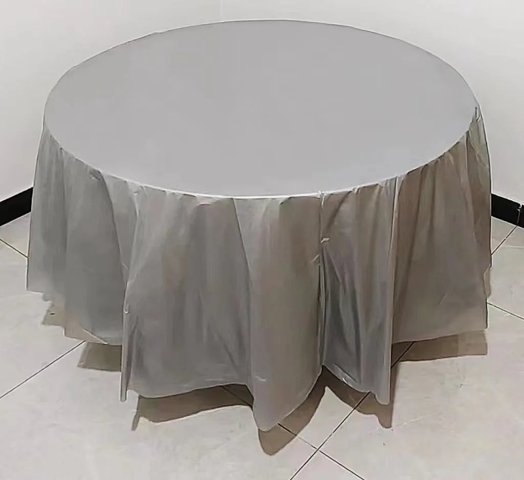 A round table covered with a white or light gray disposable tablecloth, set up for an event.