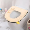 Una cubierta de asiento de inodoro impermeable y suave color beige dentro de una taza de inodoro blanca.