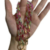 A hand holds a colorful resin chain replacement strap with pink and green hues.