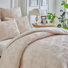A beige duvet cover set with a delicate leaf print pattern displayed on a bed.