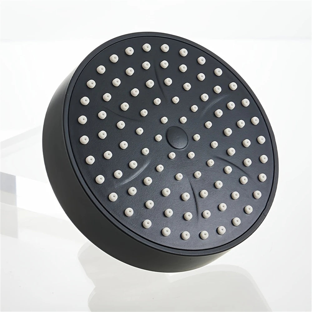 A matte black shower head with multiple small nozzles is shown on a white surface.