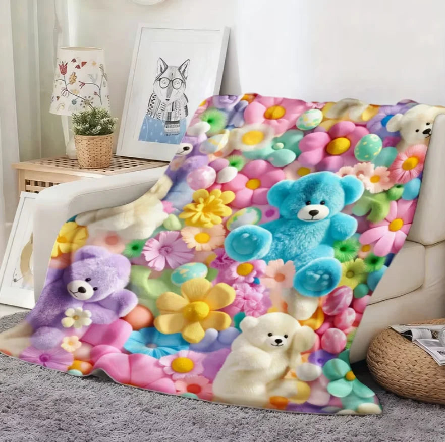 A colorful flannel throw blanket featuring various pastel-colored teddy bears and floral patterns.
