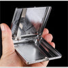 A hand holds open a classic stainless steel cigarette case with an embossed pattern.