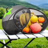 A black metal fruit basket with a mesh cover filled with various fruits outdoors.